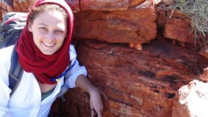 Tanja Boask stands in front of some of the oldest stromatolites that appear in a red layered rock