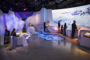 Visitors of different ages look at climate change visualizations in museum exhibit hall