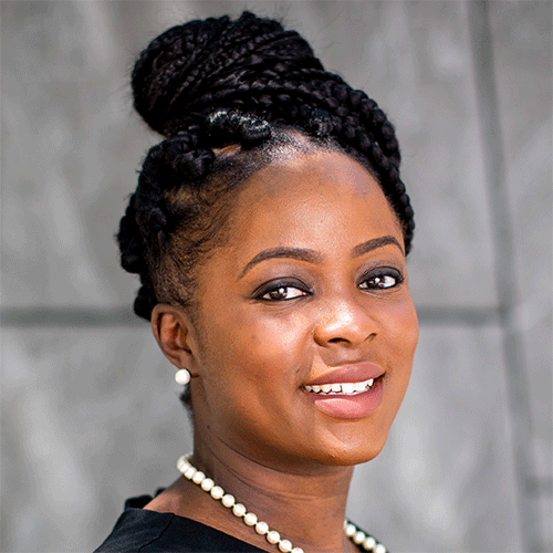 Headshot of a woman standing outside with a pearl necklace and black top.