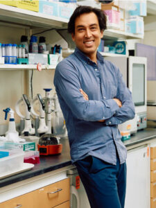 Jay Mahat smiling with arms crossed in a lab