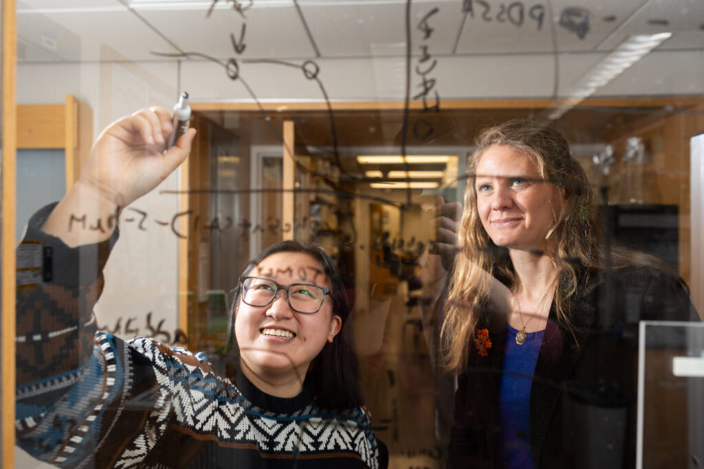 Annette Jun Diao and Seychelle Vos write equations on glass 