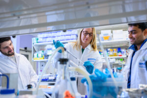 Stefani Spranger pipettes in the lab alongside two other scientists