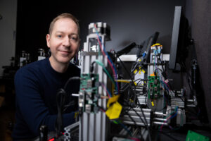 Steve Flavell in a lab with a device that has many colorful wires