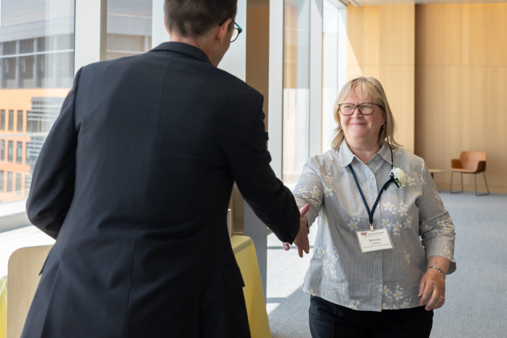 prize winner shaking hand with nominator at the podium