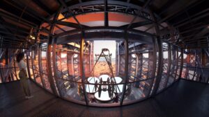 Fisheye photo of a woman on a balcony overlooking the Giant Magellan Telescope